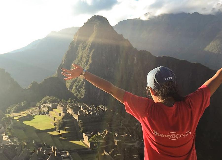 A woman in front of Machu Picchu with her arms up